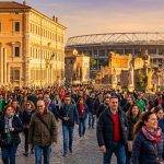 Foule de supporters marchant devant des ruines romaines avec un grand stade de football en arrière-plan à Rome.